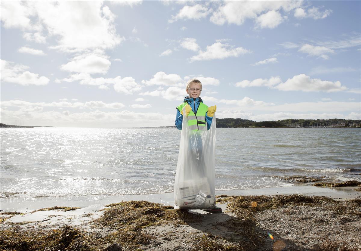 Gutt som rydder en strand. Foto. - Klikk for stort bilde